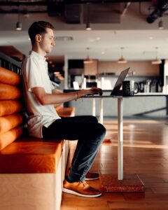 man in white t-shirt and blue denim jeans sitting on brown leather couch  to sign up for Hustle & Pivot's latest trends and insights to help stay ahead of the game.