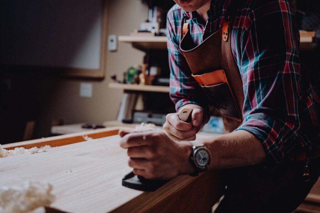 A man working on a piece of wood. Starting his won woodworking business.